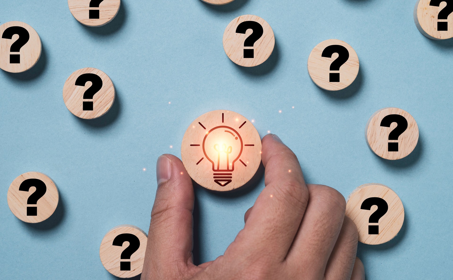 Hand holding glowing light bulb inside magnifier glass among question mark for focus and concentrate of creative thinking idea and problem solving concept.